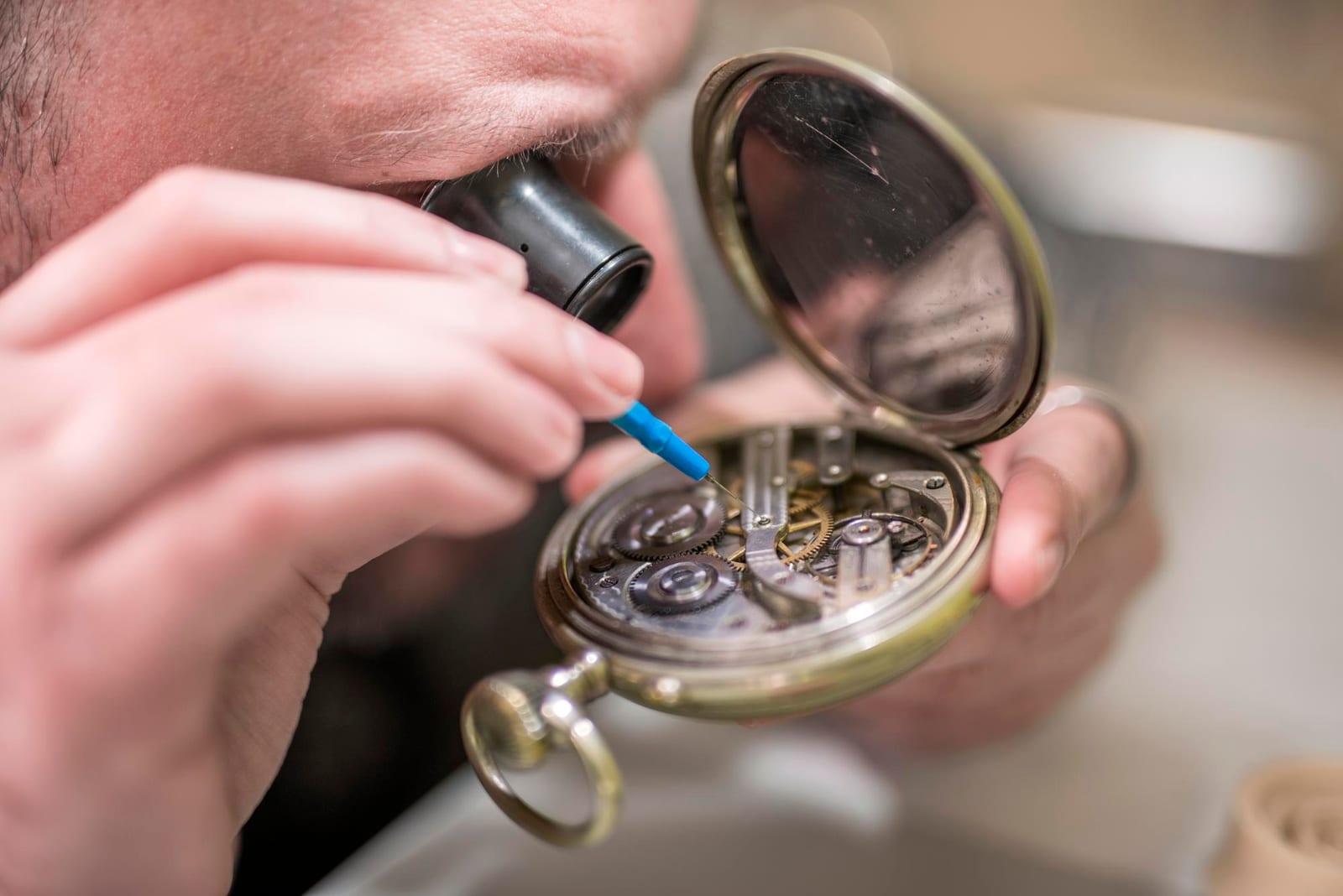 Orologiaio con lente da occhio al lavoro su un movimento aperto con un oliatore